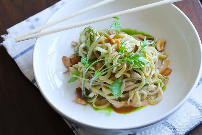 Raw vegan Asian cucumber noodles with a spicy tahini sauce , cashews, and baby kale